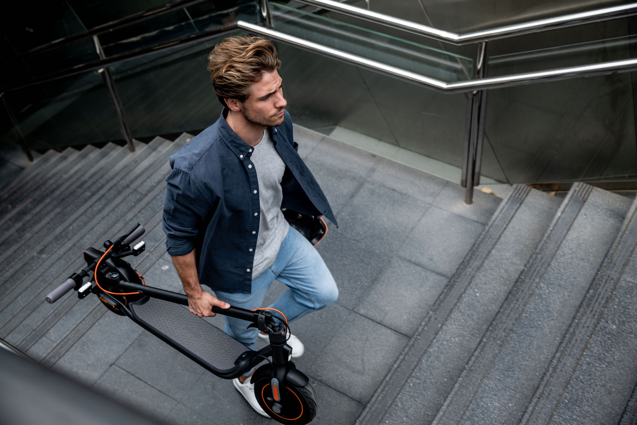 Ninebot KickScooter F40I_Lifestyle picture_Man walking up stairs_Folded KickScooter